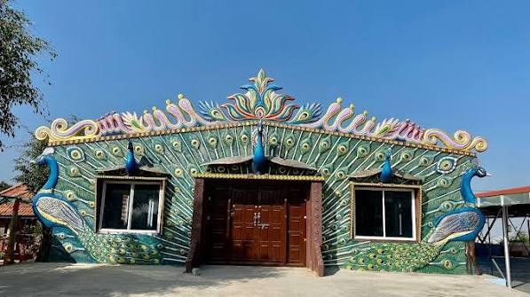 The hall's peacock-motif facade with sculpted feather work and carved entrance doors