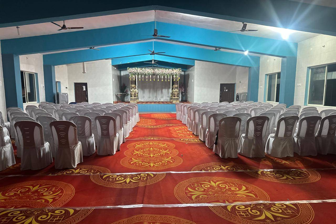 Shanmuga Hall set for a wedding — rows of covered chairs either side of the carpeted aisle leading to the decorated stage